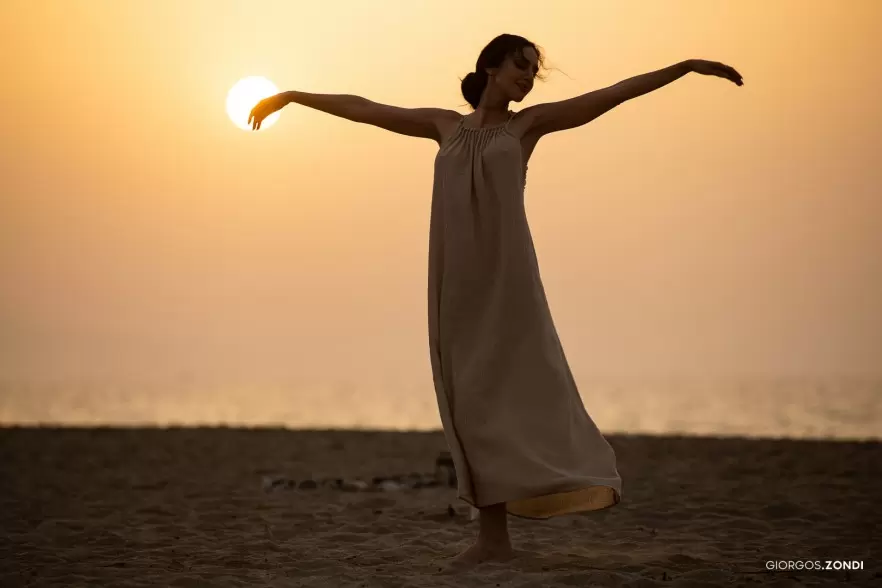 Lifestyle photo of a girl dancing at sunset on the beach of Nautilux Hotel, highlighting the beauty and freedom of a seaside evening.