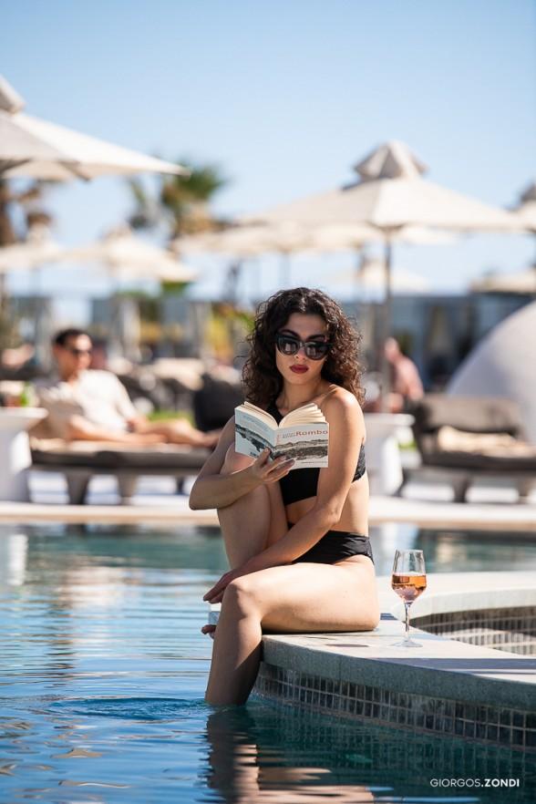 Lifestyle photo of a girl reading a book while relaxing by the pool at Nautilux Hotel, showcasing a serene and luxurious atmosphere.