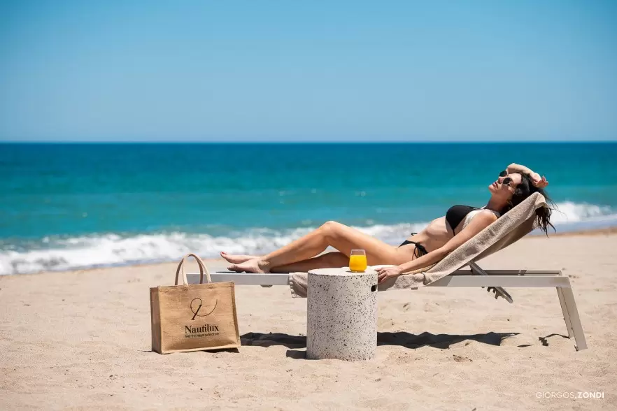 Lifestyle photo of a girl sunbathing at the beach of Nautilux Hotel, highlighting the relaxing and luxurious beachfront experience.